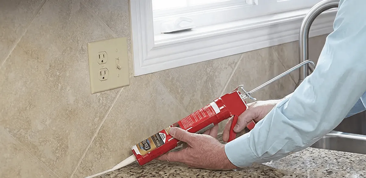 Handyman applying caulk along a kitchen backsplash and countertop seam in Chula Vista, CA